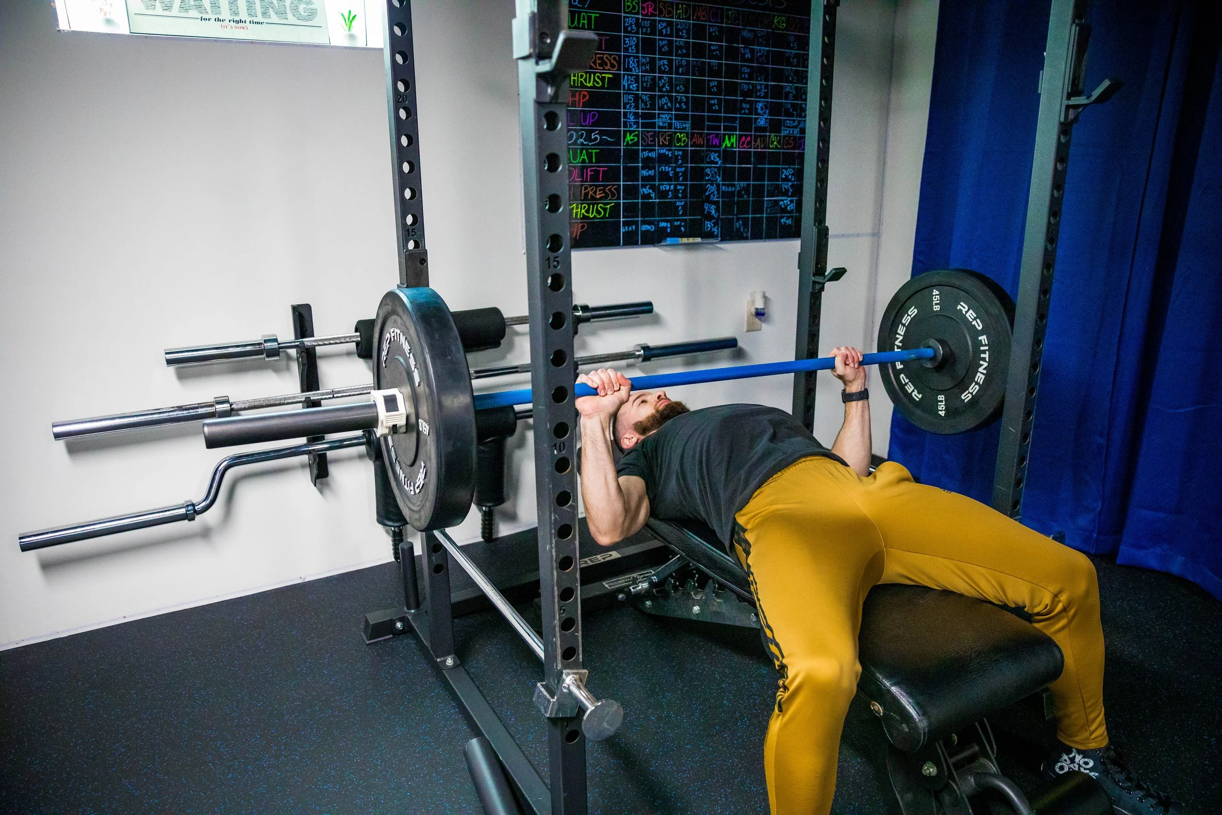A man lying on a bench performing a bench press exercise with a barbell loaded with weights.