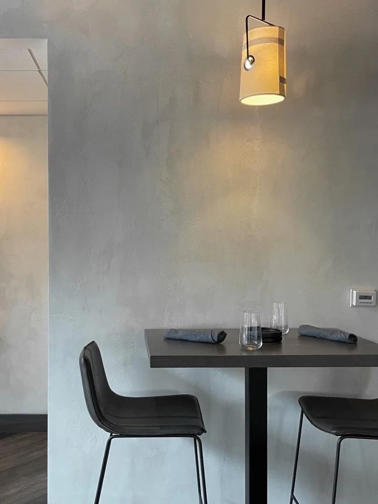 Hand-applied mineral plaster in our stone finish, built in successive layers and worked by hand to create a continuous surface across this restaurant interior. A soft grey surface that shifts gently between matte and burnished as light moves through 