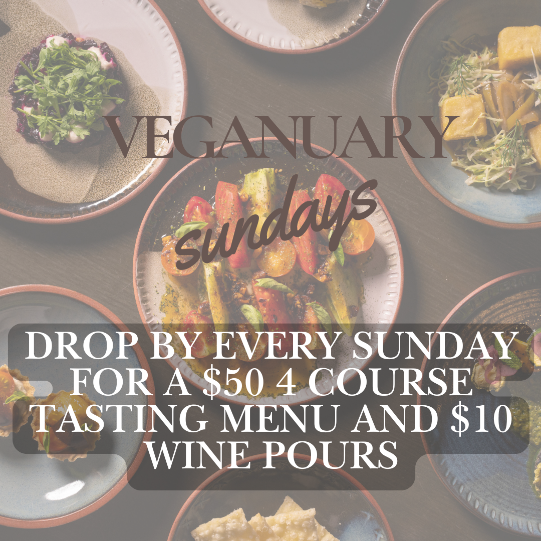 Assorted color dishes with vegetables and plants on a dark table promoting vegan Sunday tasting menu and wine pours.