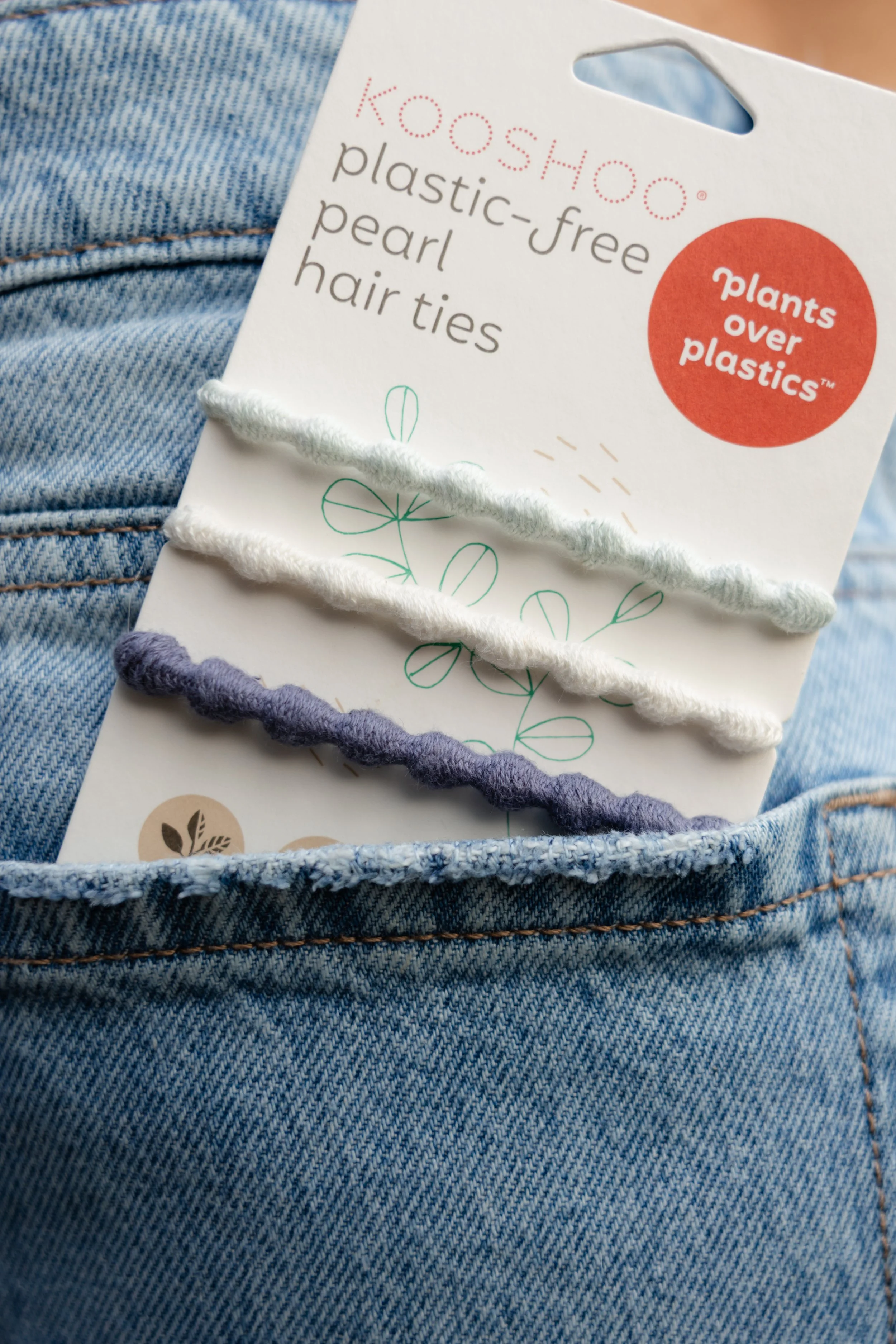 Flat lay product photography of KOOSHOO plastic-free crochet hair ties, bracelet hair ties, and everyday headband in natural tones on a linen background