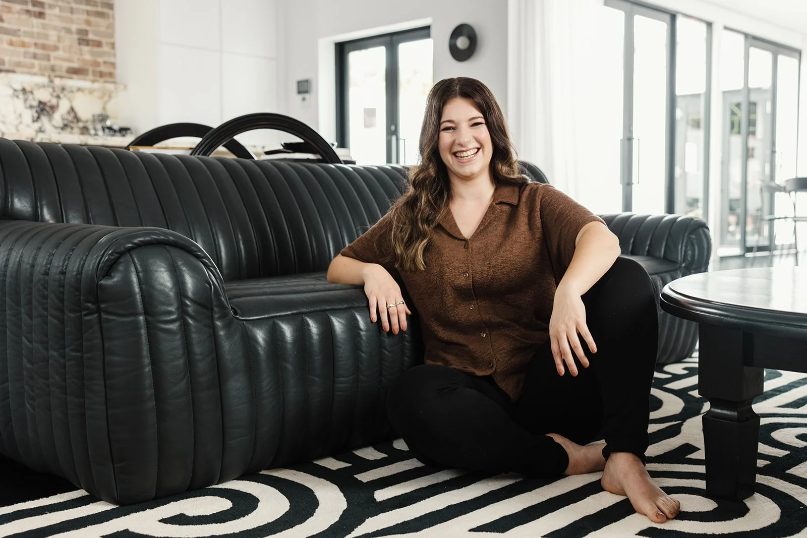 Valentine Aouad, founder of Green Socials, smiling on a dark sofa in a bright studio