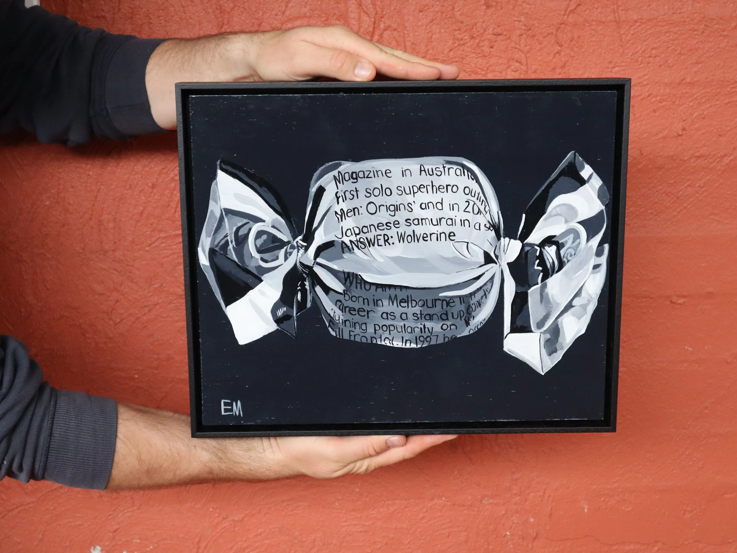 hands holding black and white painting framed in black shop