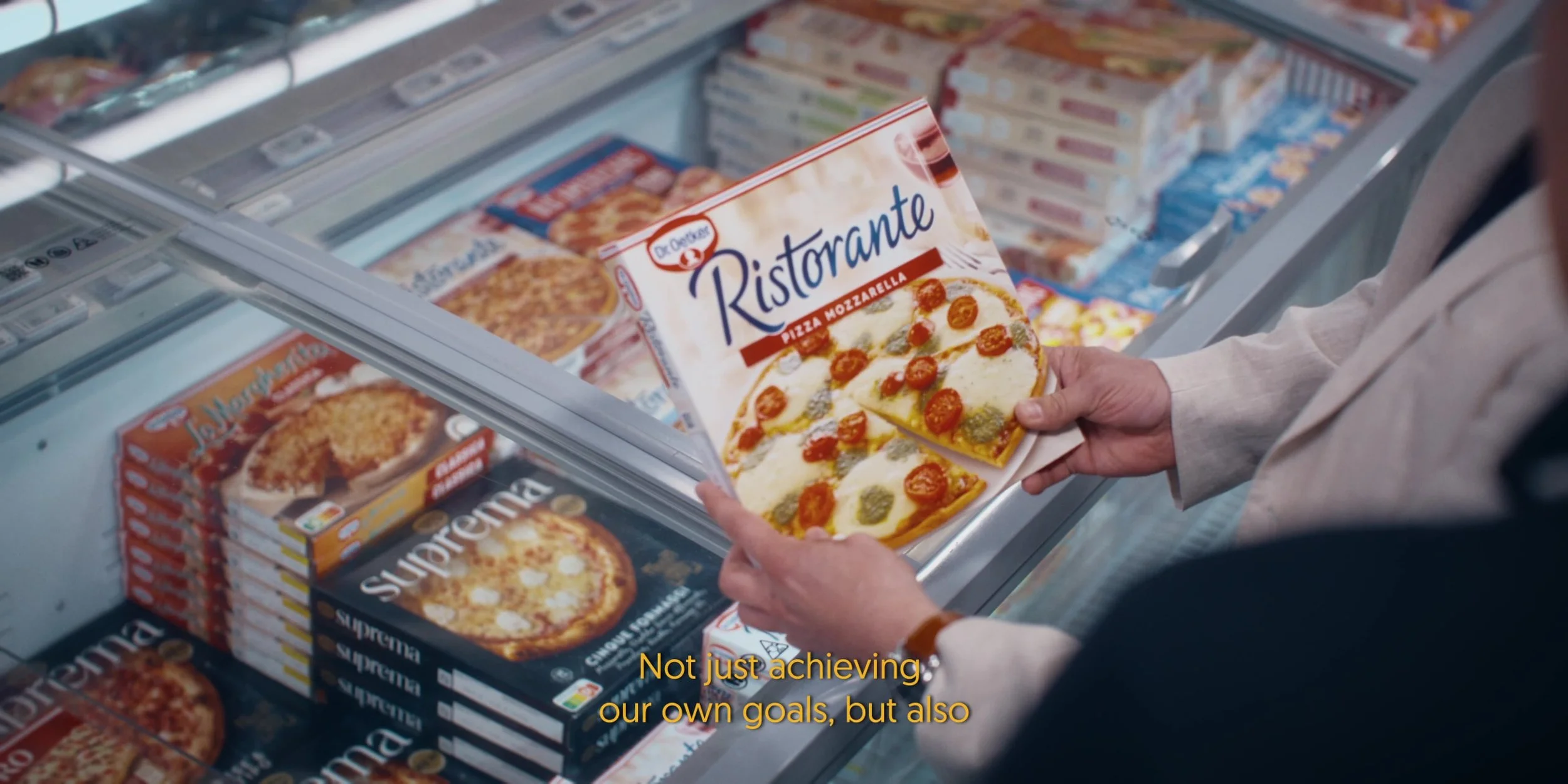 Person holding a box of Dr. Oetker Ristorante pizza creamy mozzarella in a grocery store aisle.