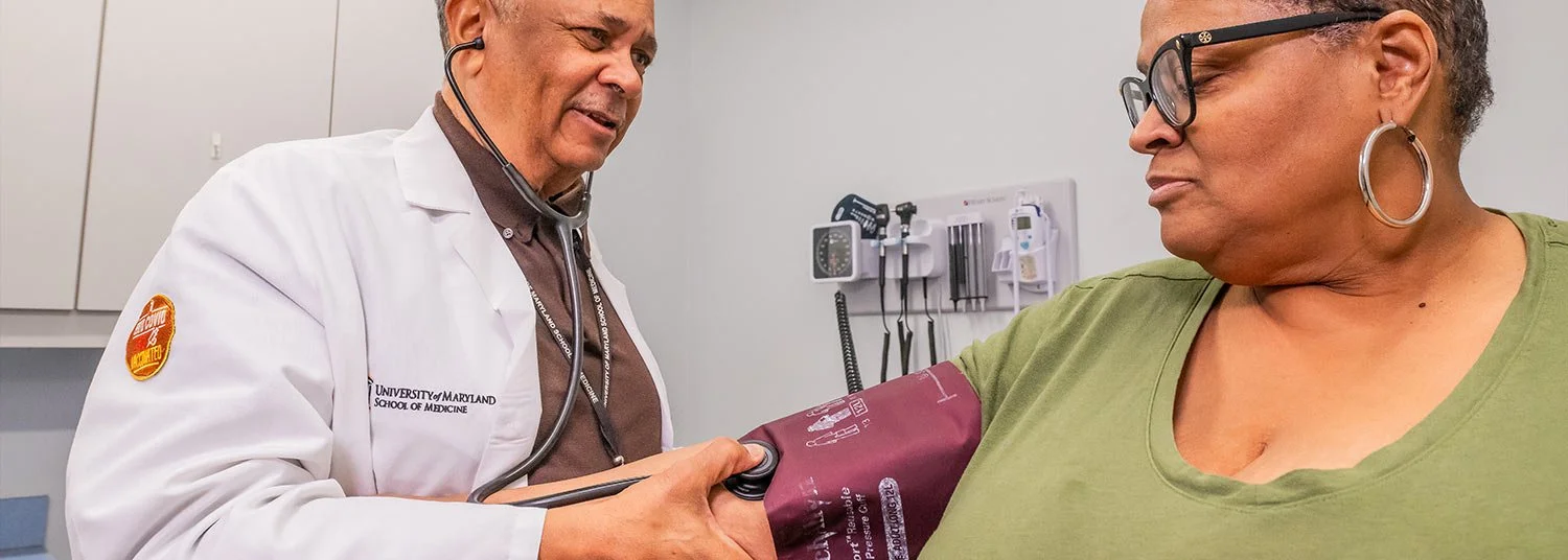 Doctor measuring a woman's blood pressure using a sphygmomanometer in a medical office.