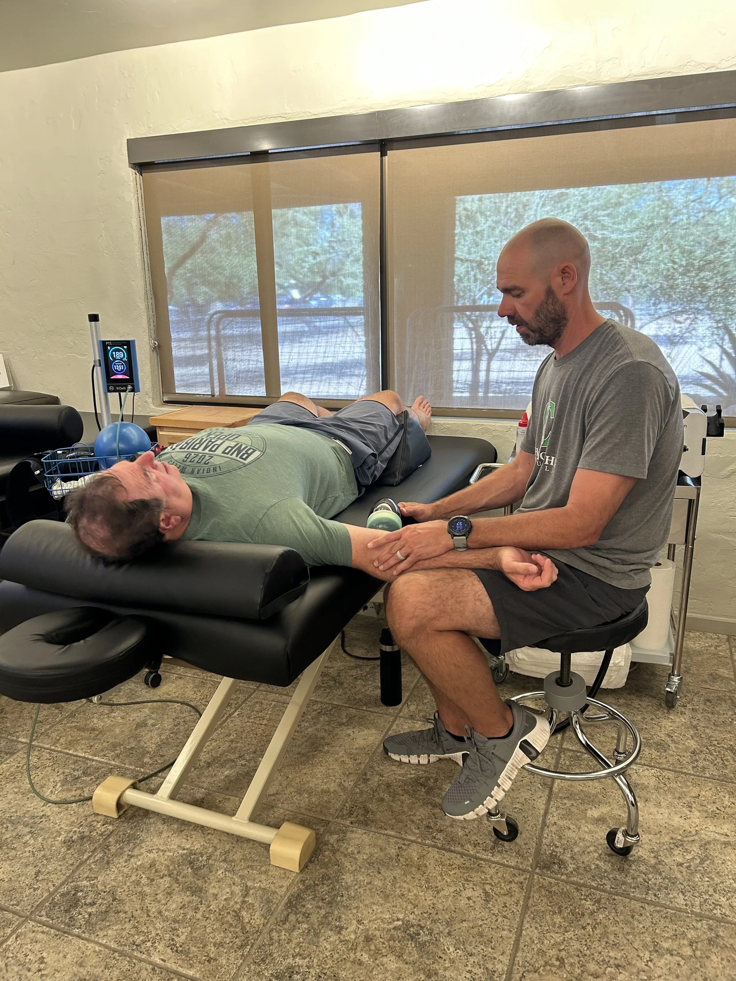 Man performing shockwave therapy on an arm injury at Championship Institute in Tucson Arizona