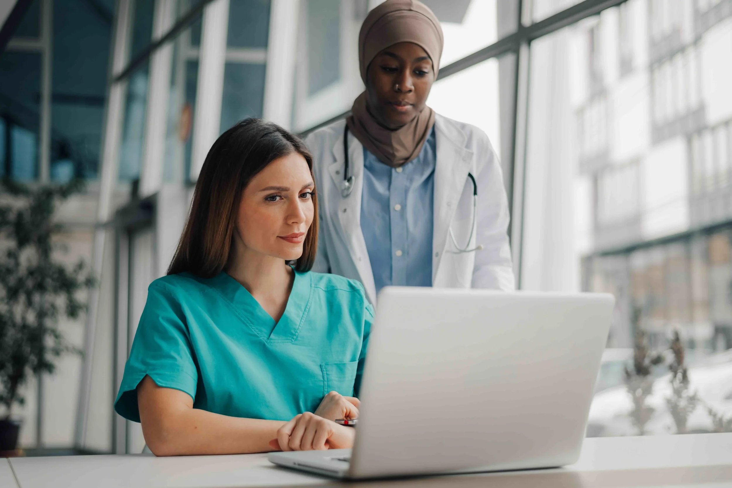 Image of two healthcare professionals at a laptop, working on CultureAlly's ConnectED eLearning