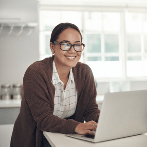 Manager smiling at camera behind computer looking at the CultureAlly Workplace Sensitivity and Respect resource.