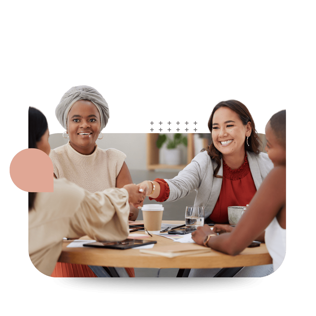 Four women sitting around a table in a meeting room, engaging in a discussion at a CultureAlly in person workplace training.