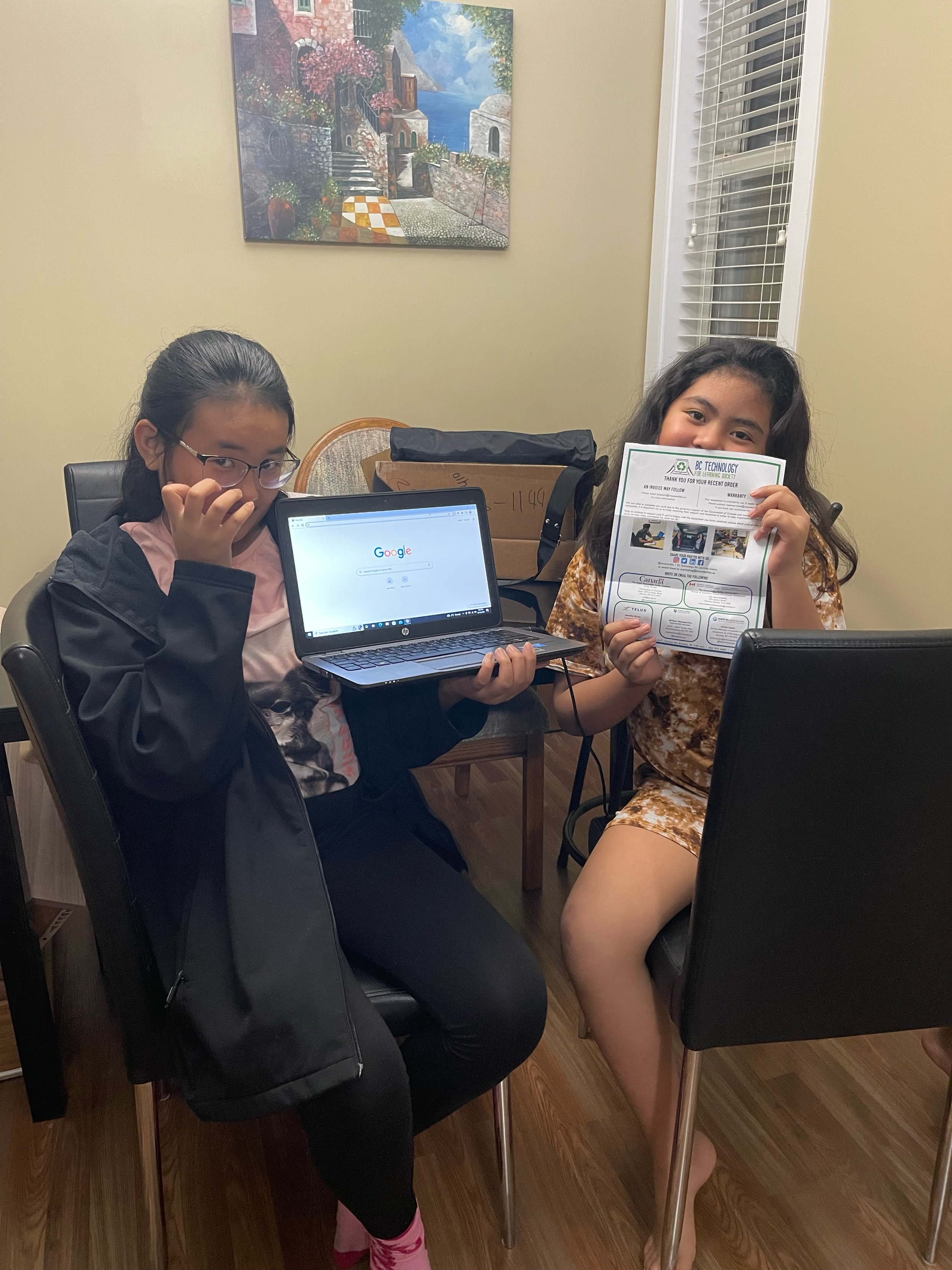 Children holding up refurbished computers they received from BC Tech