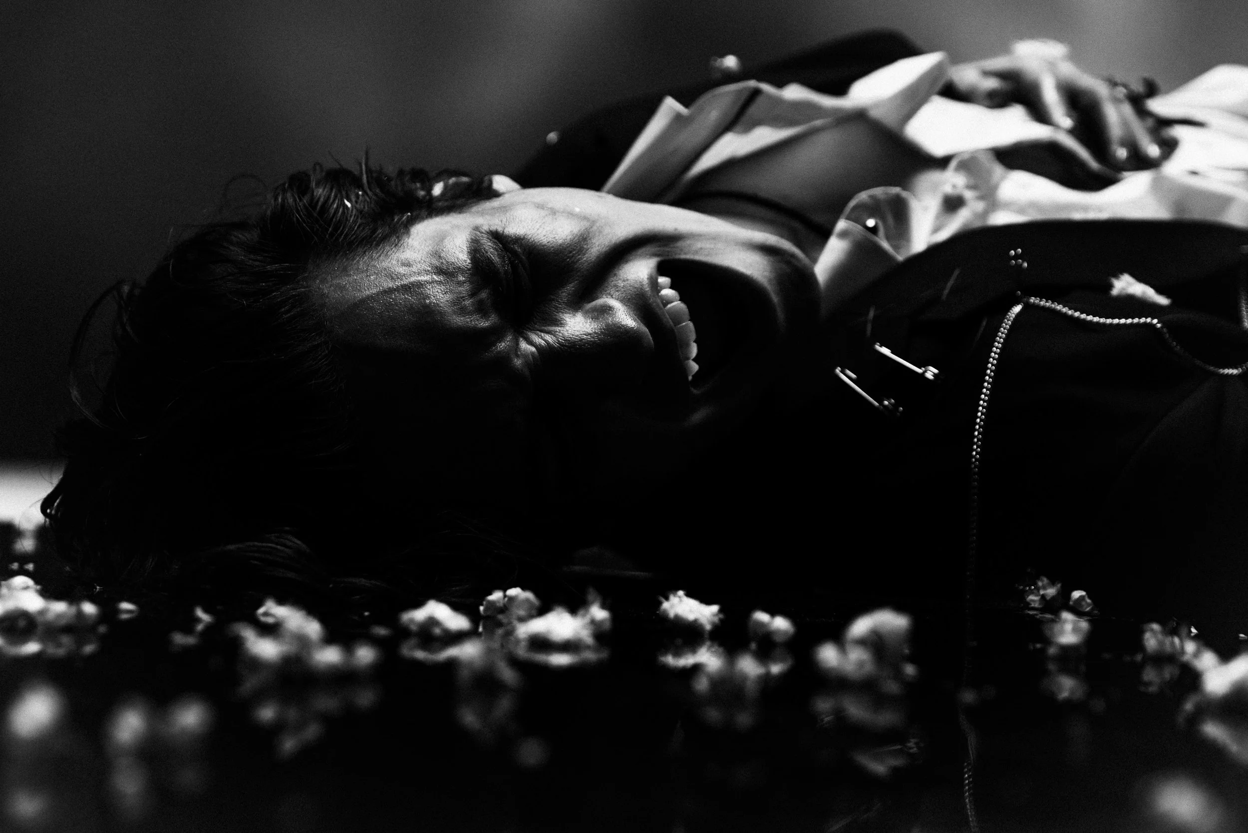 A woman lying on the ground laughing or smiling with her eyes closed, surrounded by scattered objects.