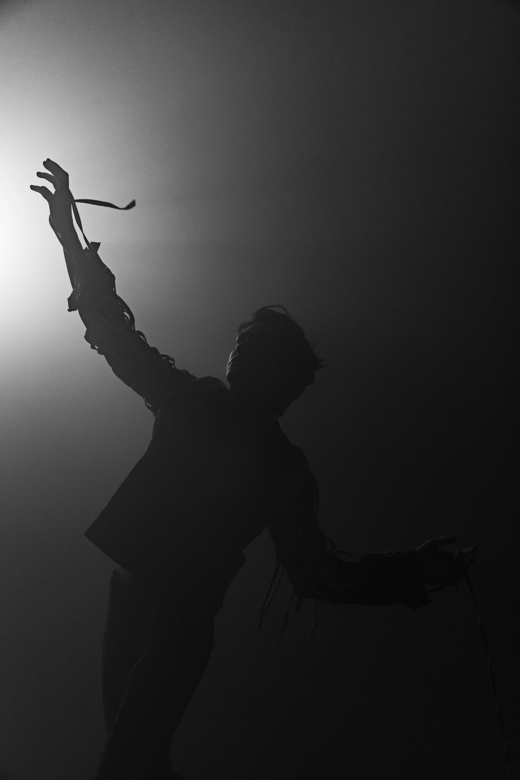 Silhouette of a person with arms raised, standing next to a bicycle against a gradient sky.