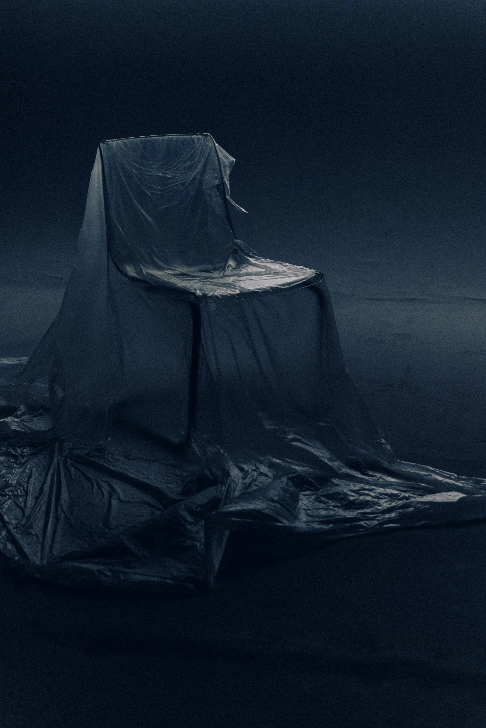 A chair and a backdrop all covered in metallic silver plastic, set against a dark background.