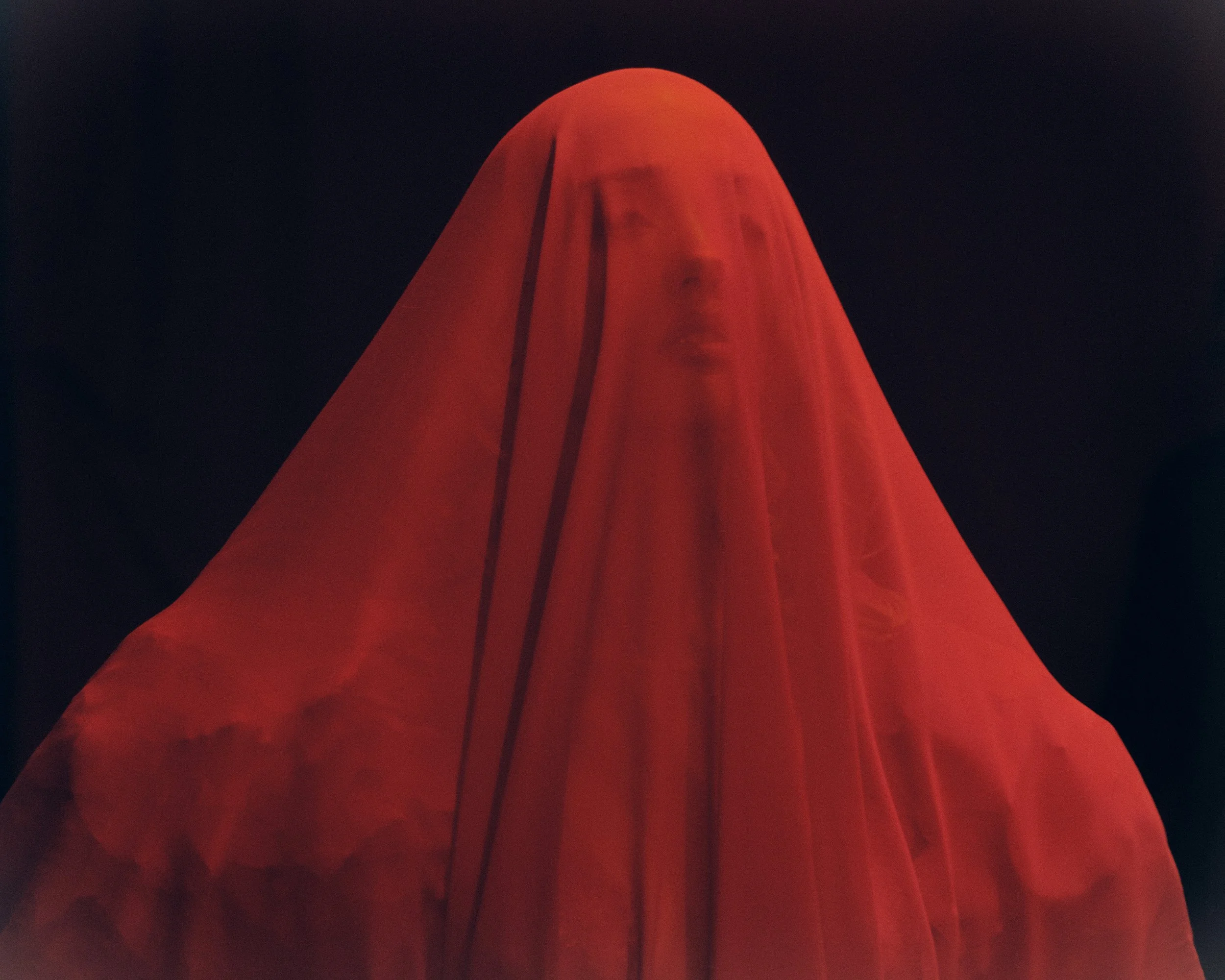Close-up of a red, tent-like fabric structure against a dark night sky.