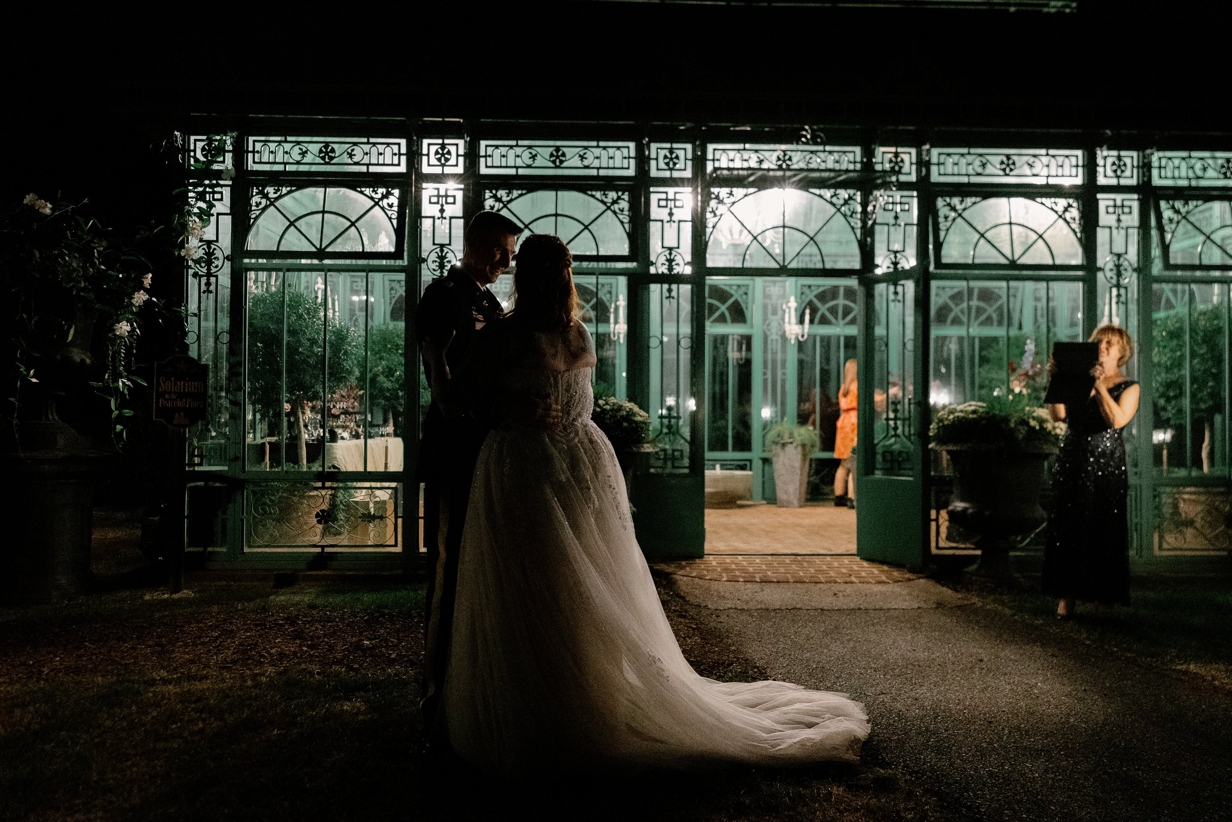 A young man with short dark hair smiling in front of a light-colored wall with textured patterns.