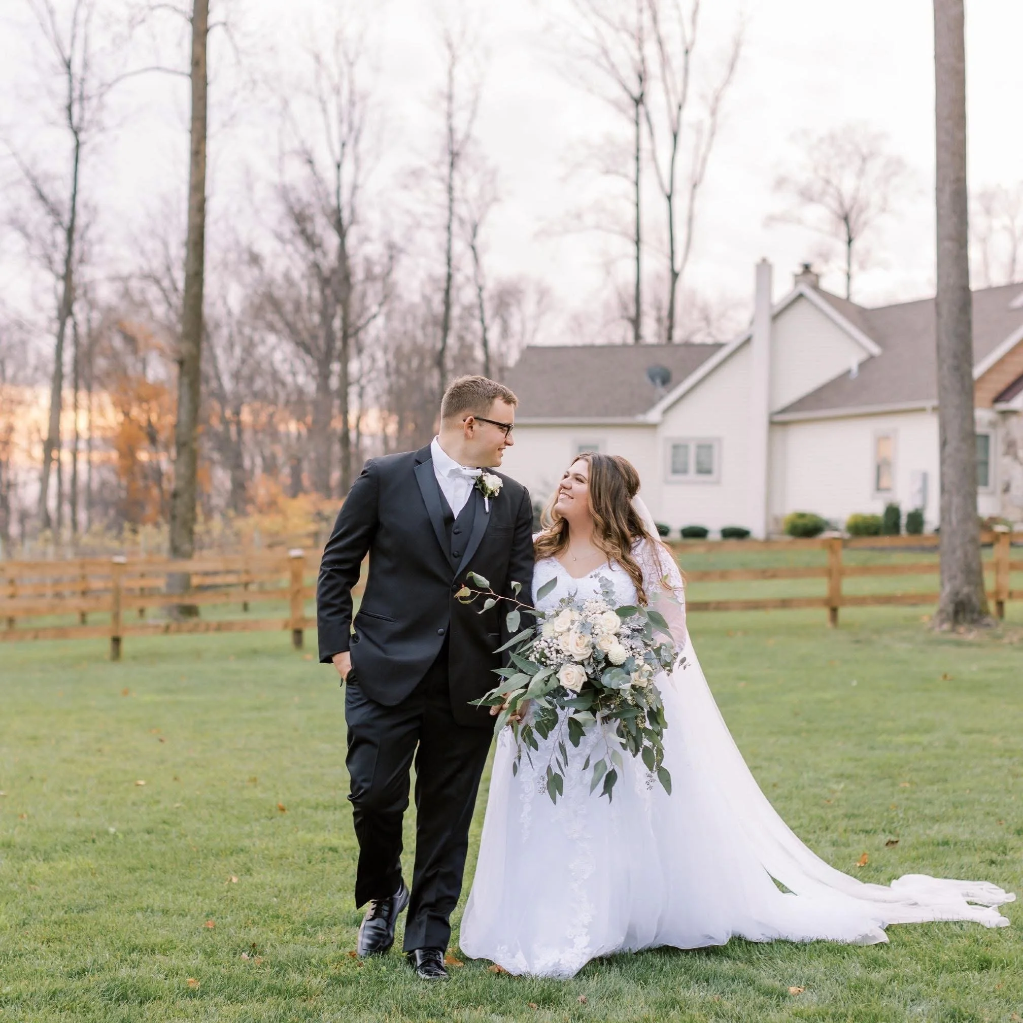 A man with curly dark hair, glasses, and a beard, looking thoughtfully to the side, sitting indoors with a blurred plant in the background.