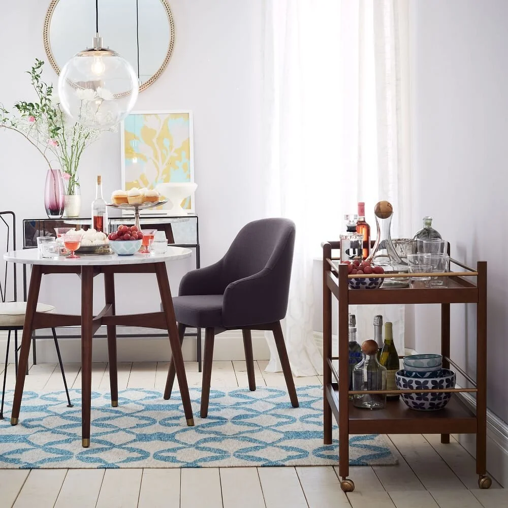  The walnut finish on this reimagined mid century bar cart from  West Elm  is what gives me all the feels. I love the shape of the handles and that it has the brass hardware to take it up a notch. 