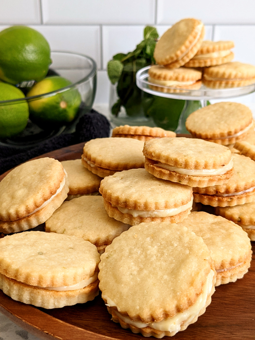Lime white chocolate sandwich cookies stacked on brown wooden cake stand