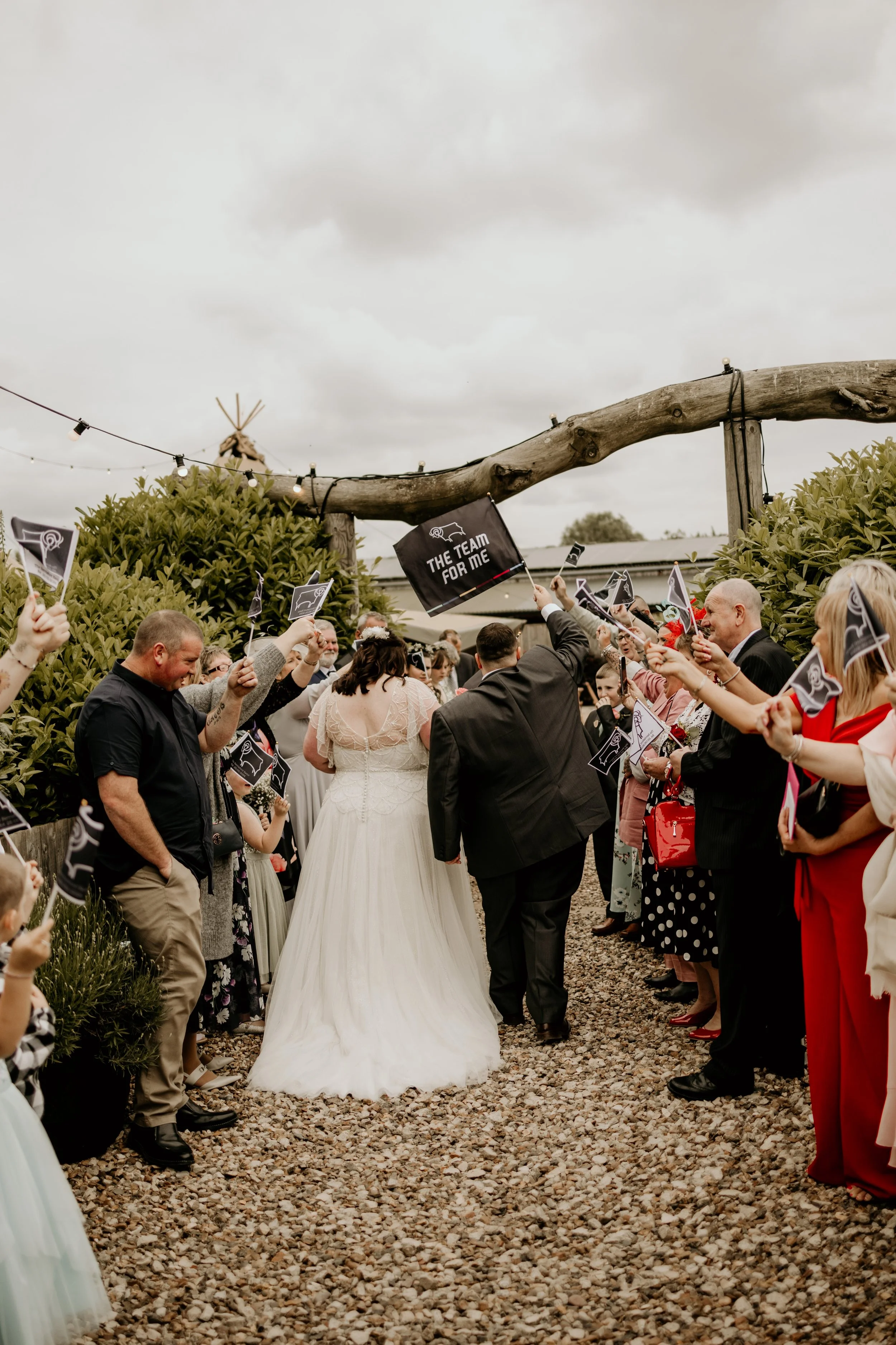 Have a relaxed wedding day shots of the couple walking with flags in their hands As well as the guests surrounding them