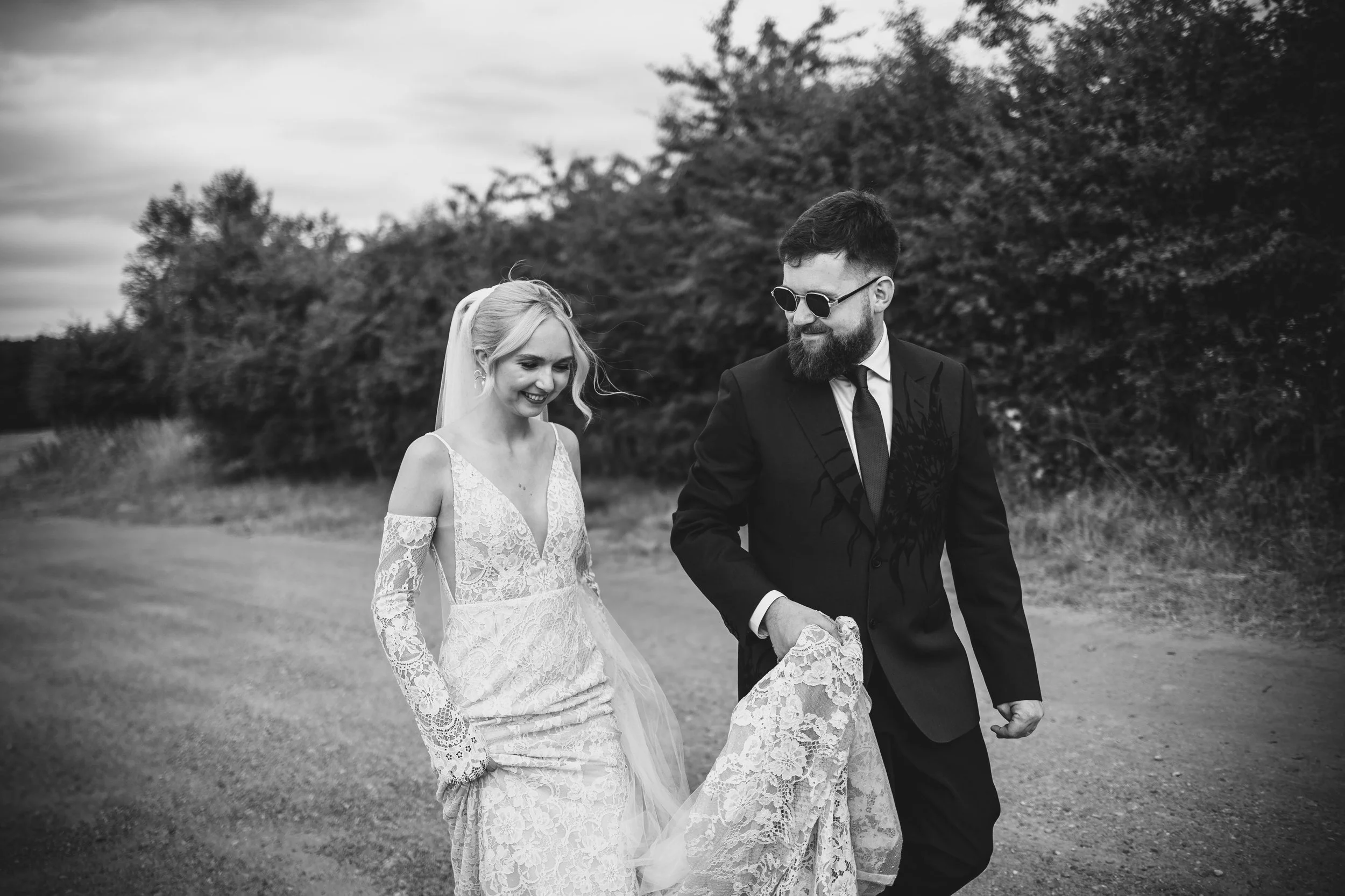 Relaxed Wedding photography in black-and-white of the couple walking through a field at the venue naturally