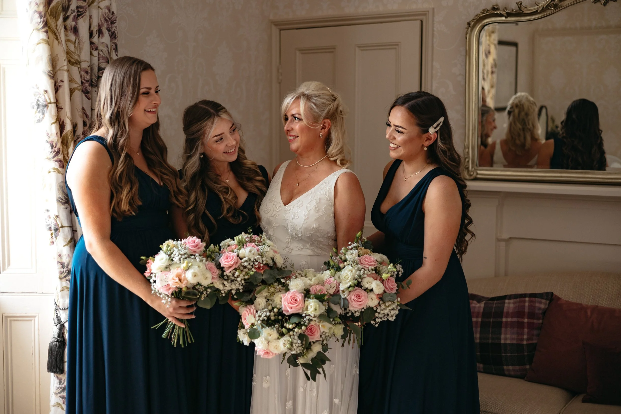 A relaxed wedding morning group shot of the bride ready with her bridesmaids