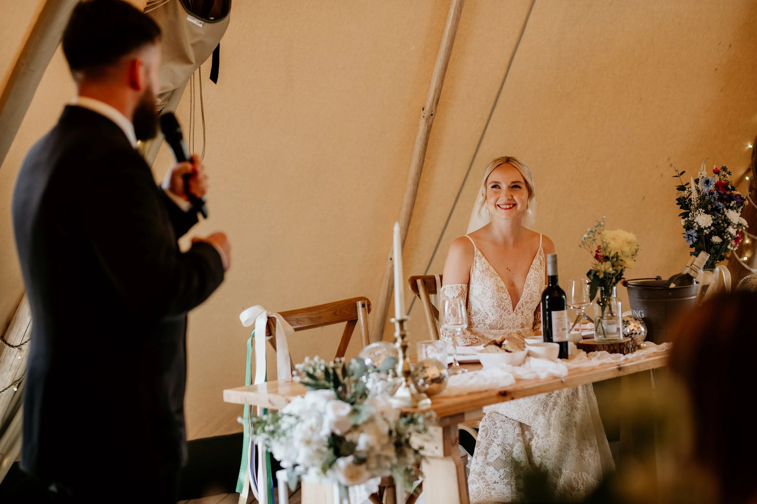 A relaxed wedding day shot of the groom saying speech and looking and smiling at the bride