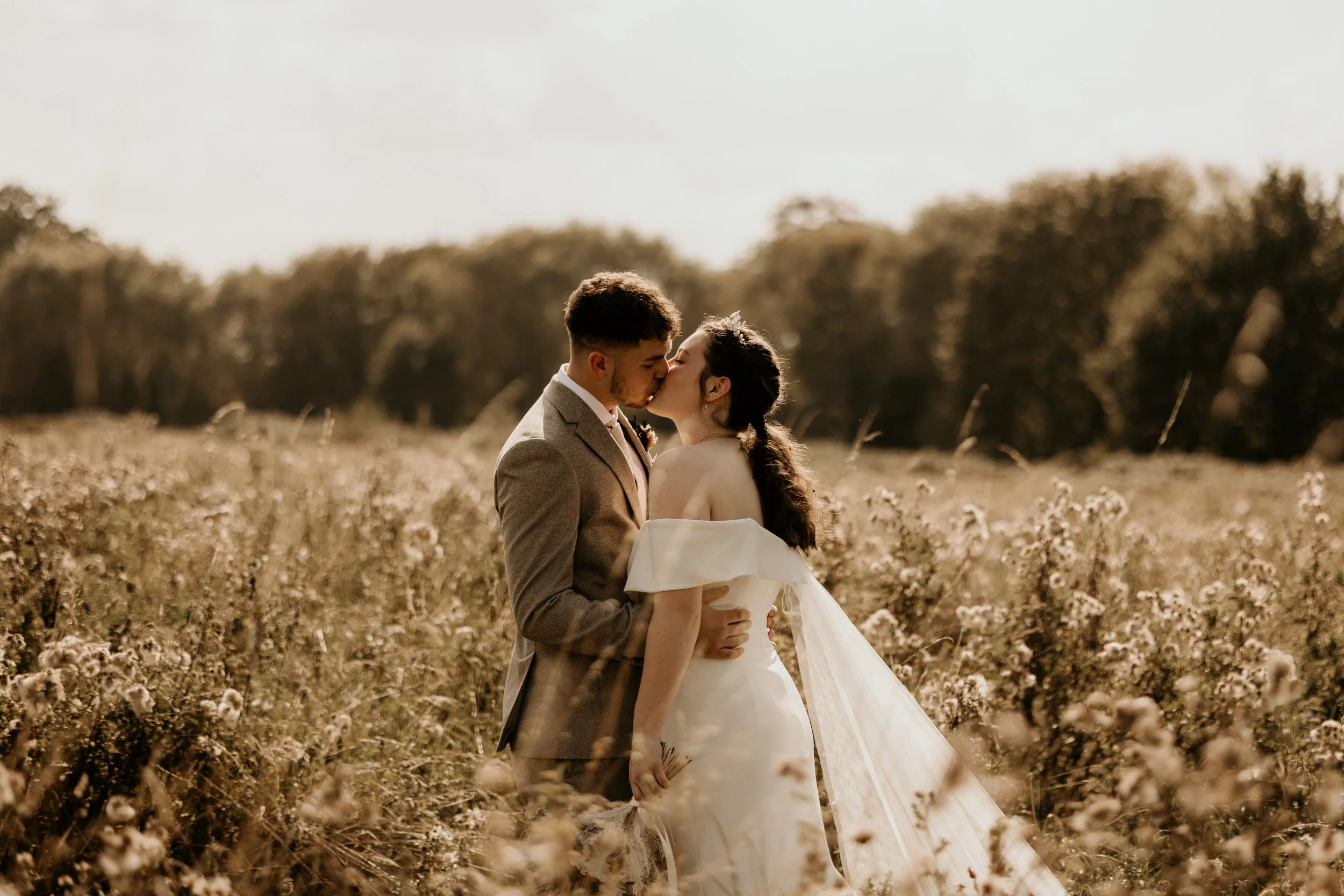 Relaxed wedding photography of a couple kissing in a wildflower field at their wedding venue