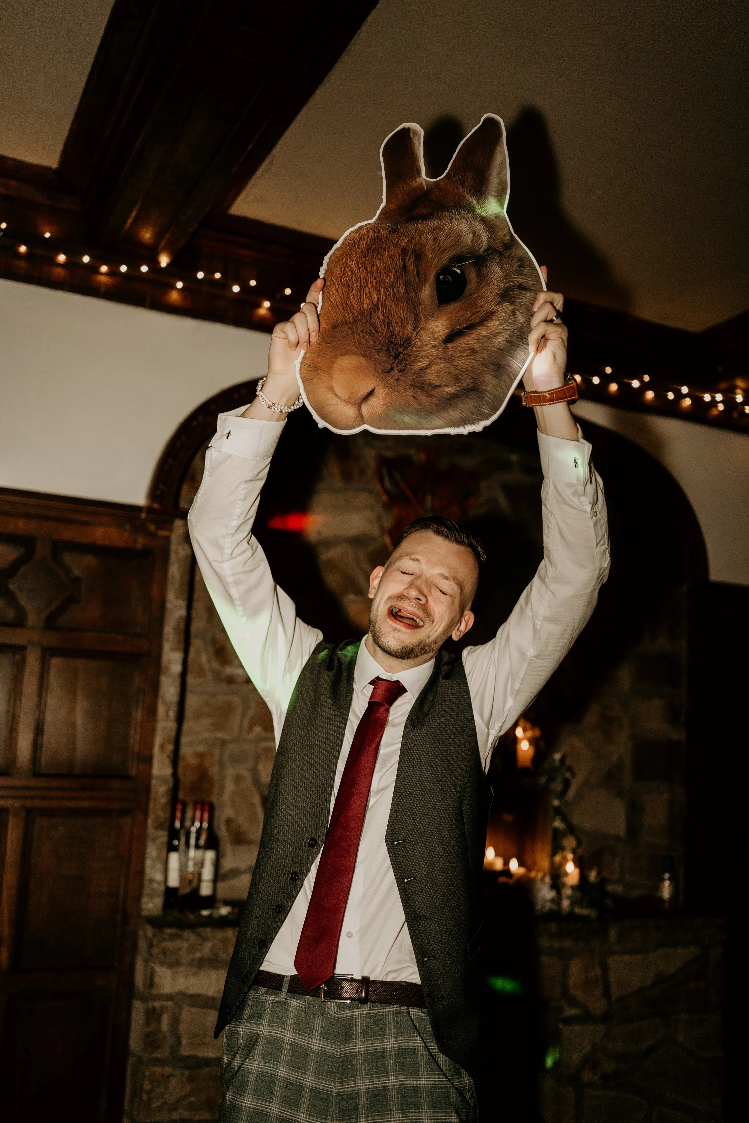 A relaxed wedding day shot of Groom holding up cardboard cut out of a rabbit head