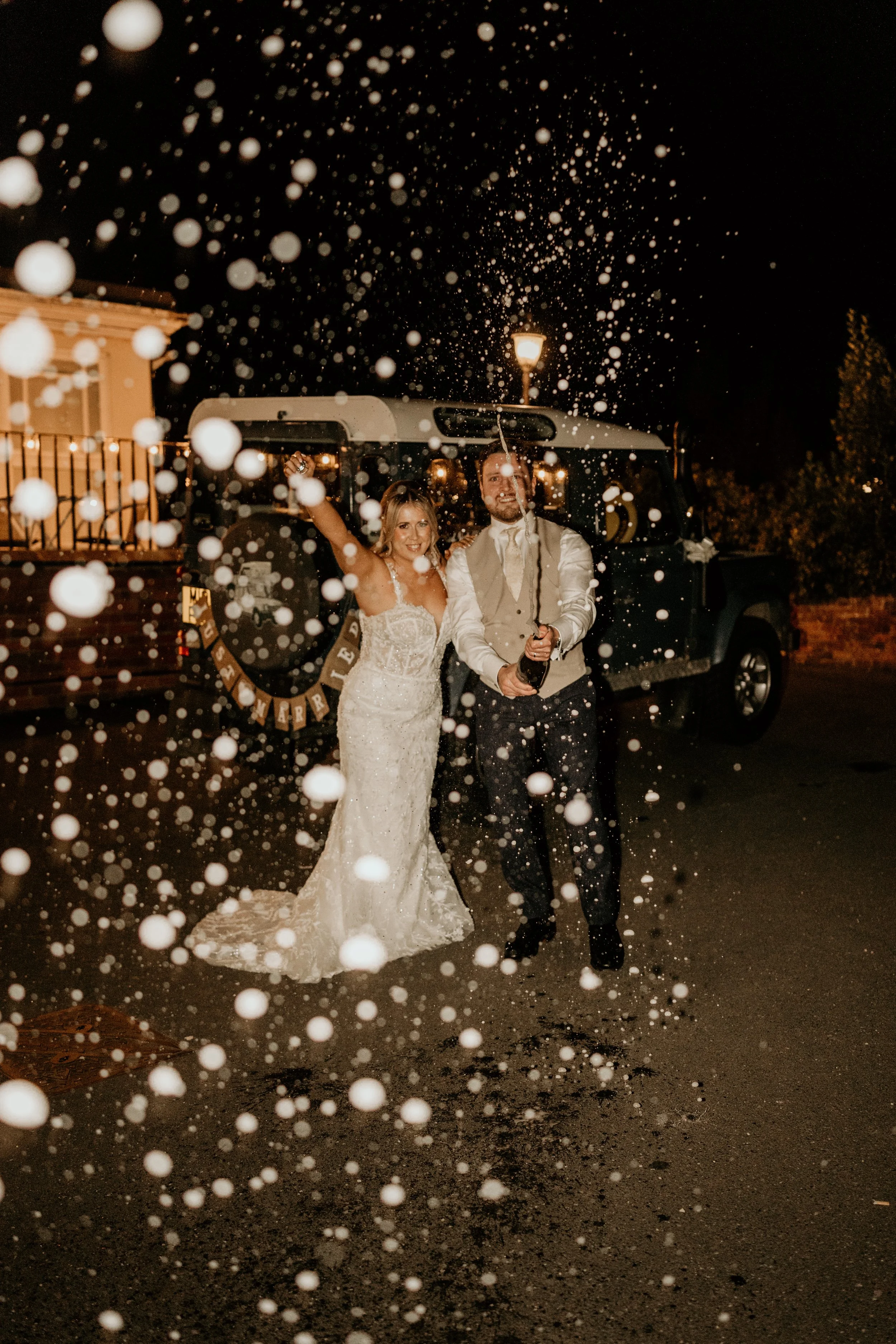 Relax wedding photography of couple popping champagne in the evening at the venue
