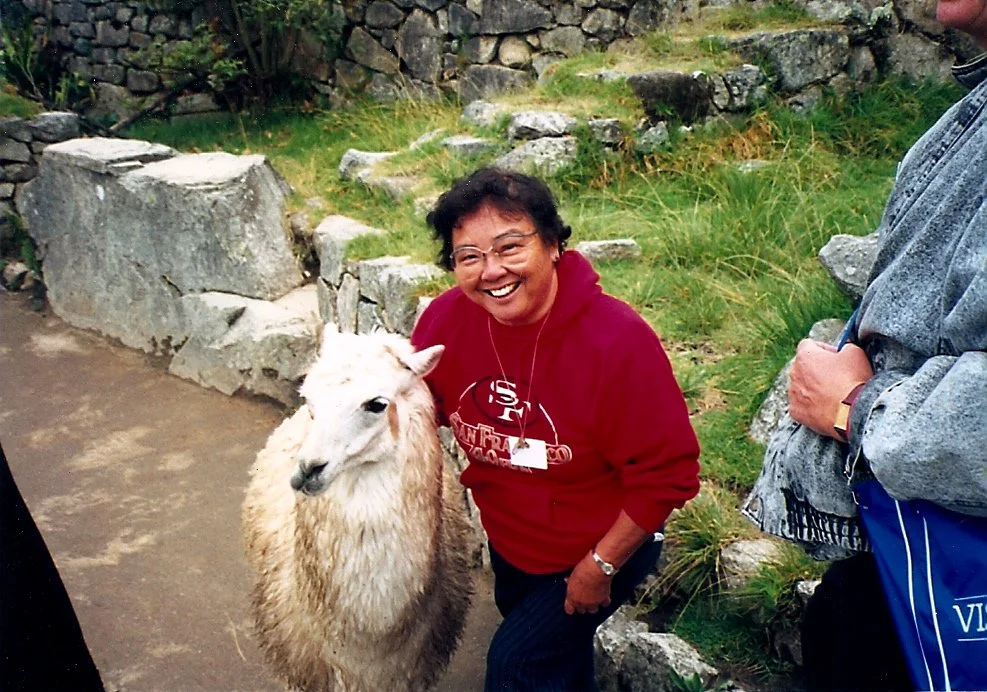Yas Morimoto smiling beside a llama in Peru