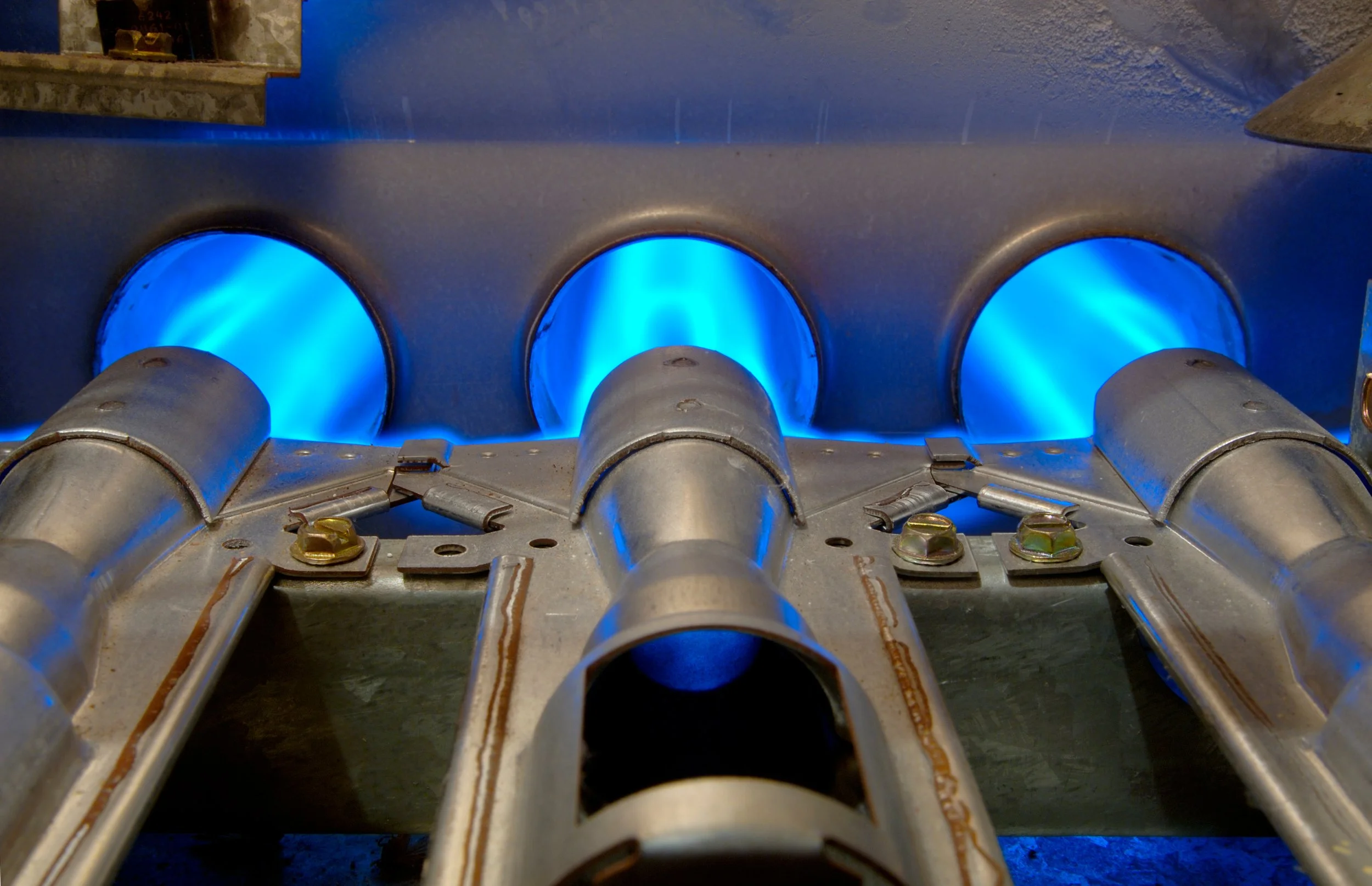 Close-up of gas burners with blue flames on industrial stove.