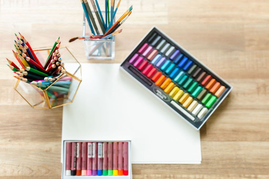 Blank paper with colorful pastels and pencils ready for an art-journaling exercise.