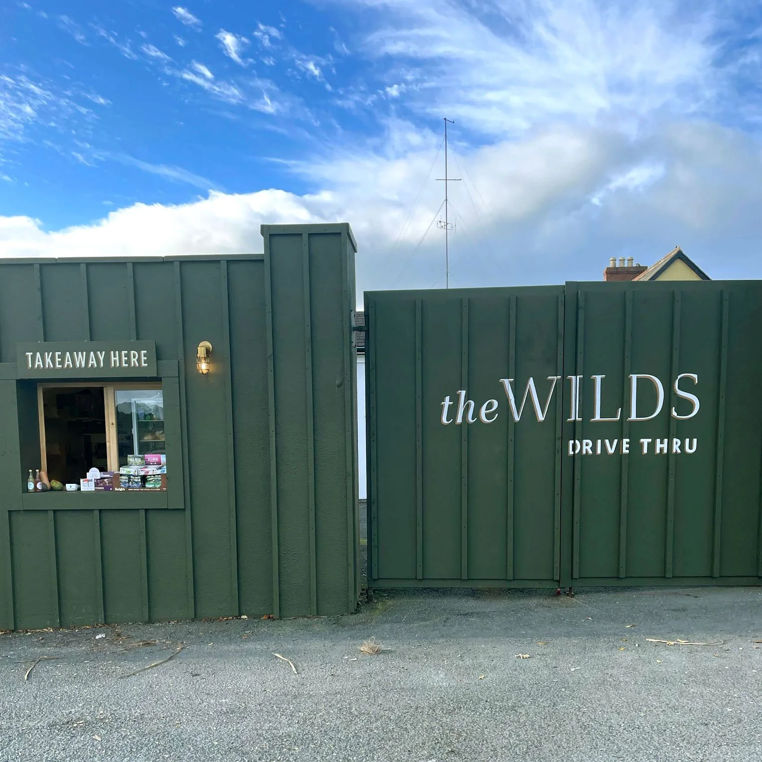 Hand-painted signage at The Wilds @ The Beehive in County Wicklow, showing the “Order Here” hatch sign above the coffee counter and the café logo with “Drive Thru” painted on the gate.