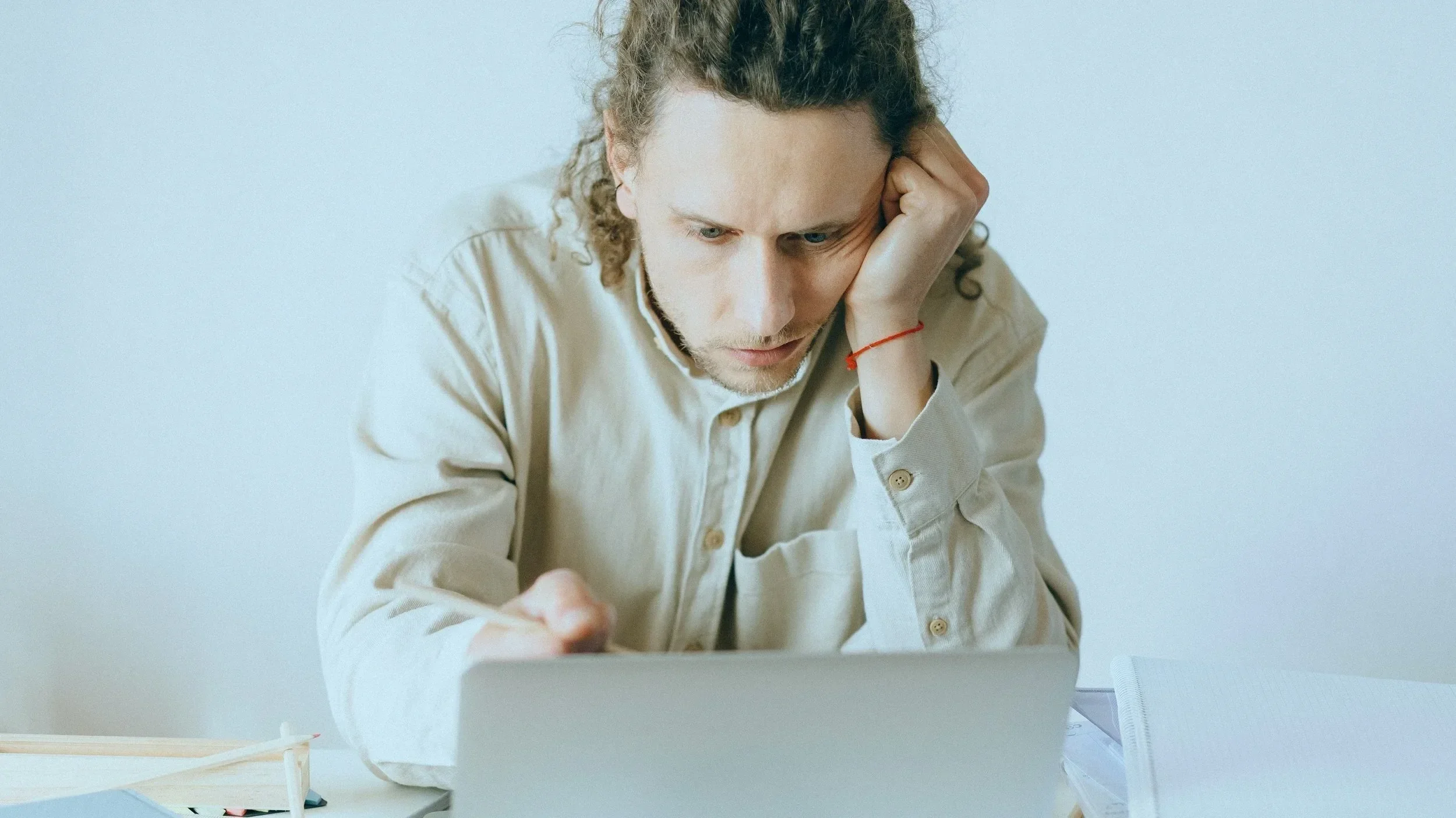 Erschöpfter Mann sitzt am Laptop und arbeitet unter Stress – Symbol für Überstunden, Burnout-Risiko und fehlende Work-Life-Balance im Arbeitsalltag.