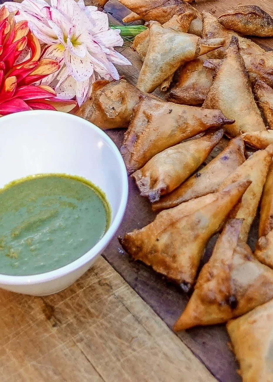 Spiced samosa appetizers with cilantro chutney, catering food display