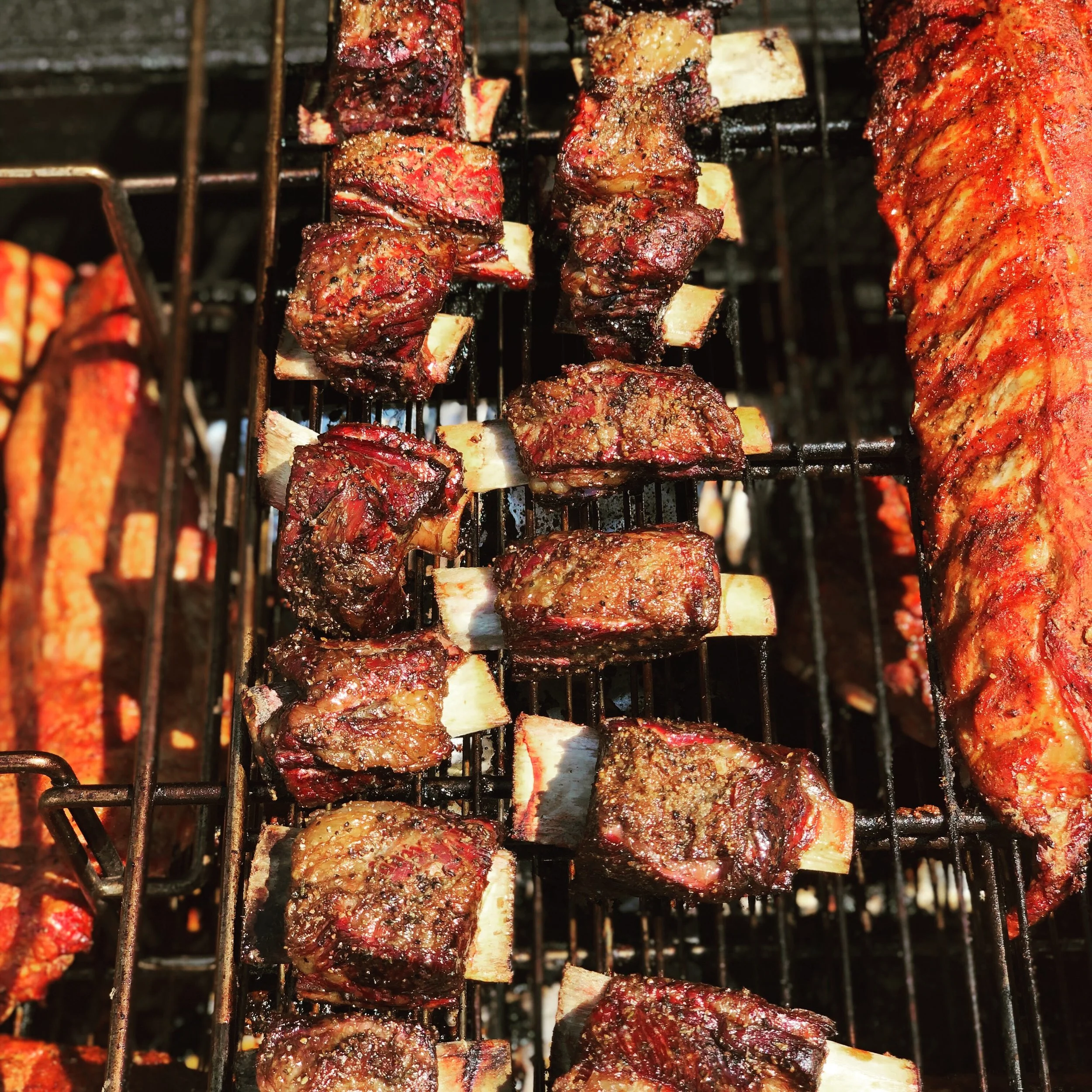 Smoked BBQ pig wings and baby back ribs on grill