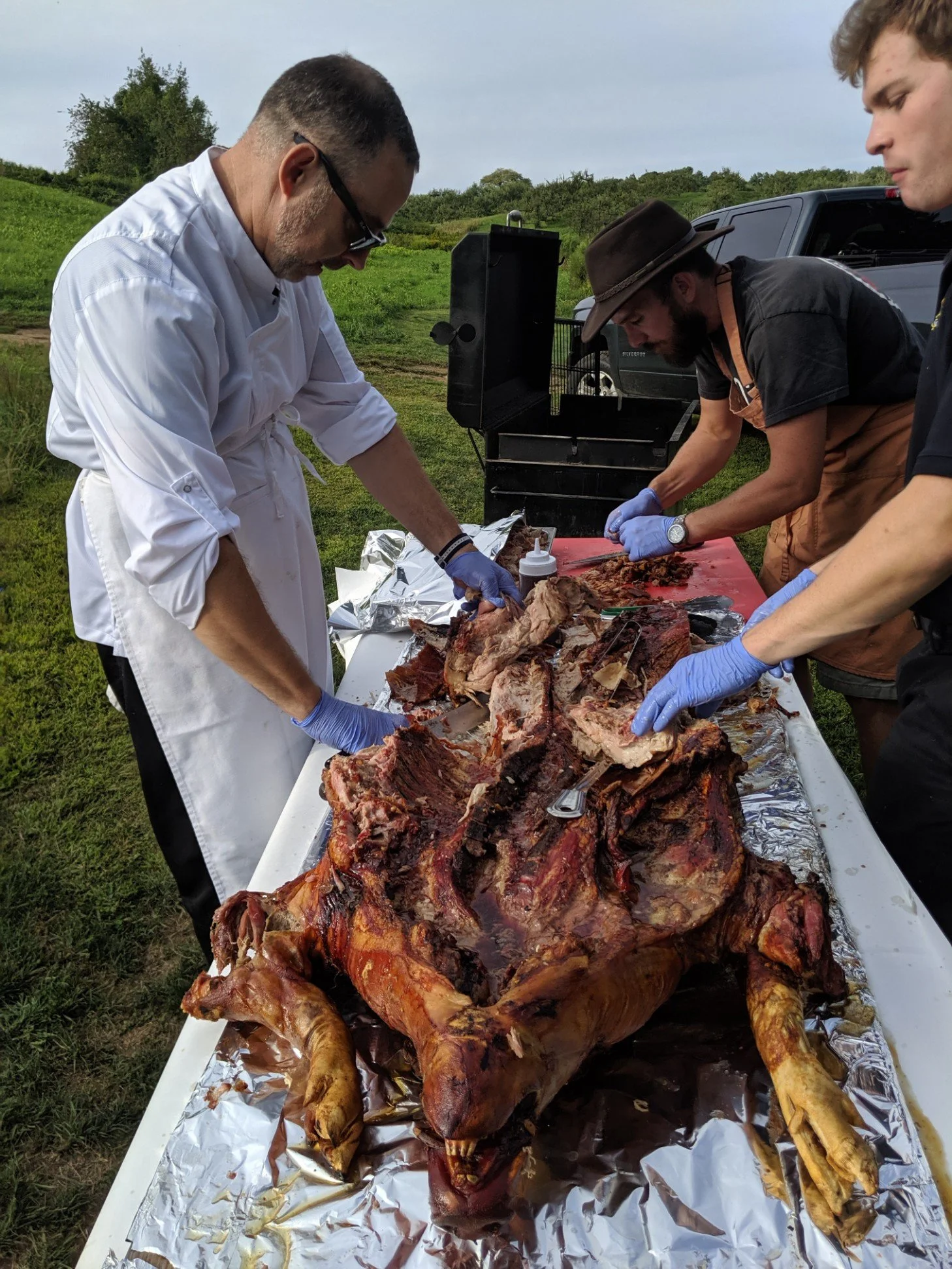 Chef picking a whole smoked pig at BBQ catering event