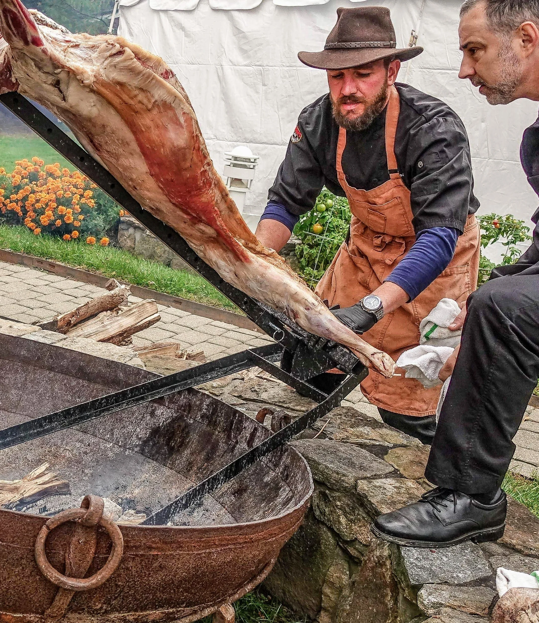 Chef managing open fire for asado-style BBQ catering