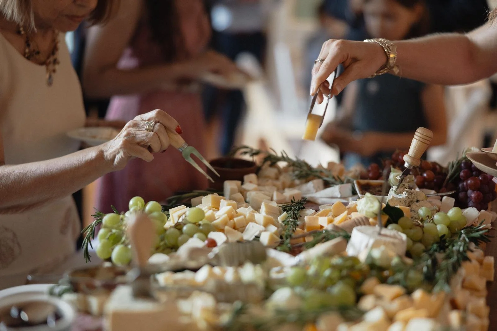 Grazing table with people getting cheese blocks