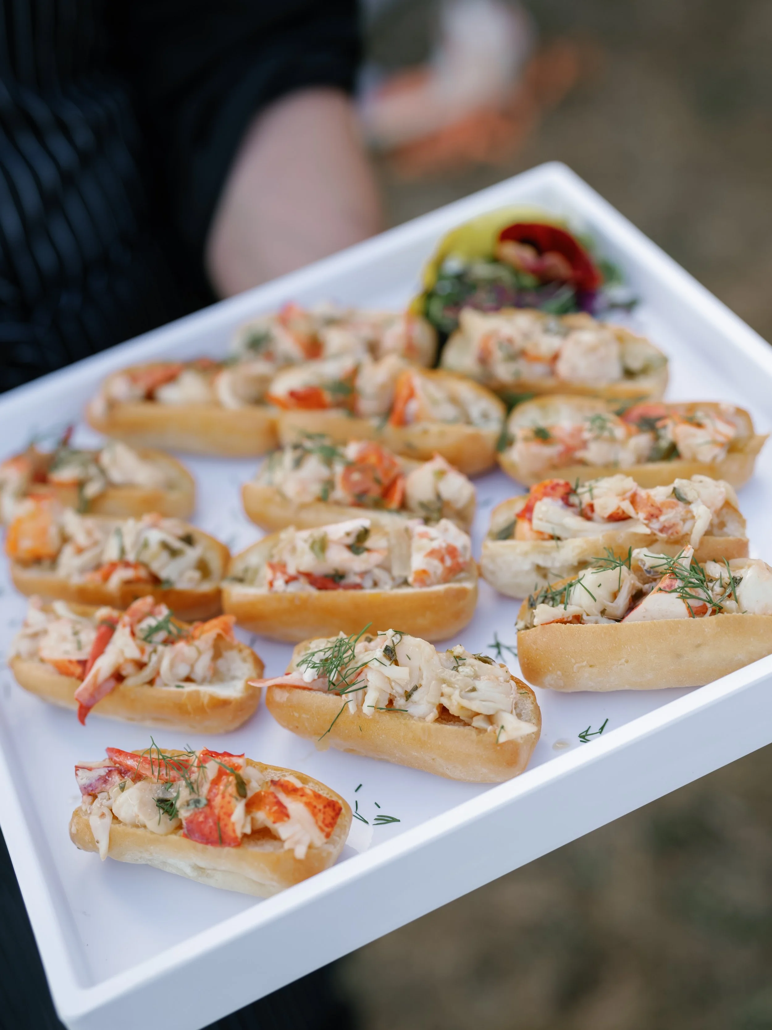 Catered lobster roll appetizers with drawn butter on mini brioche