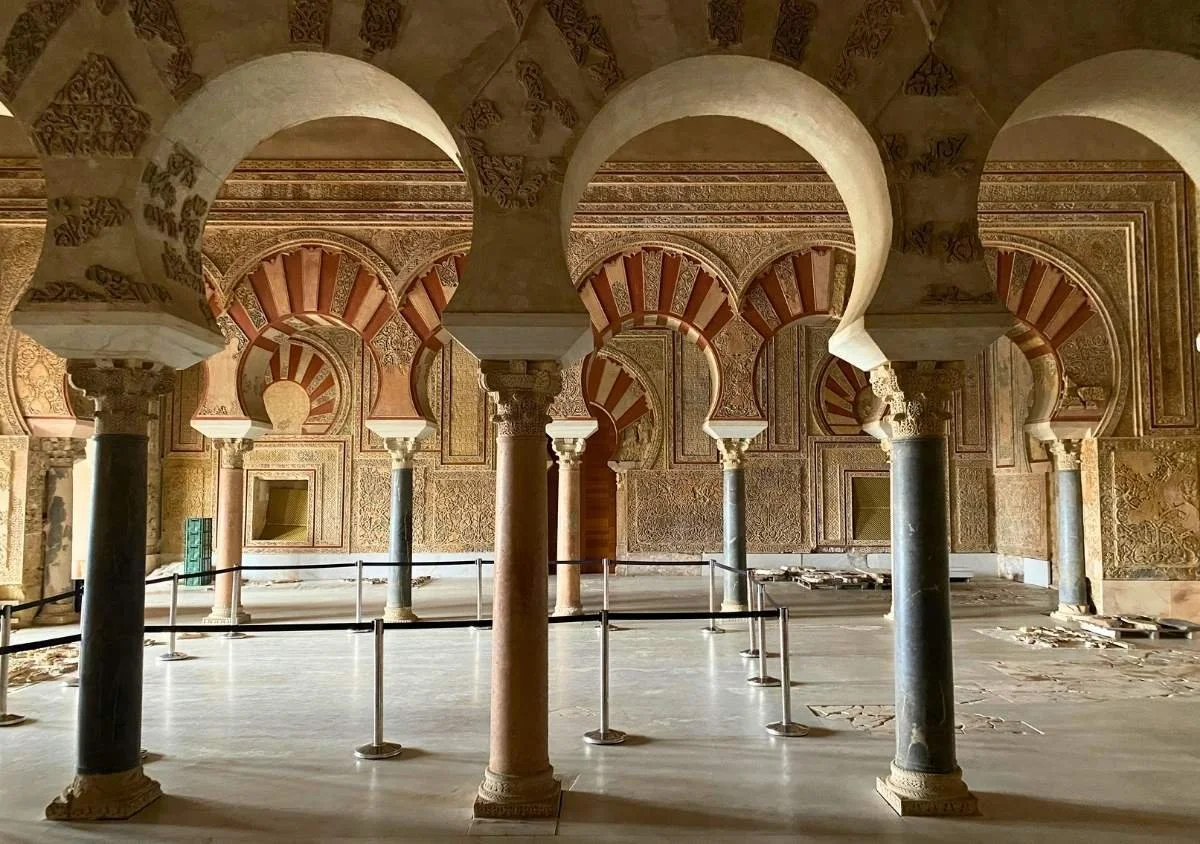 Interior of the Salón Rico at Medina Azahara, with intricately carved horseshoe arches, marble columns, and ornate Islamic decoration in the restored 10th-century ceremonial hall near Córdoba, Spain.