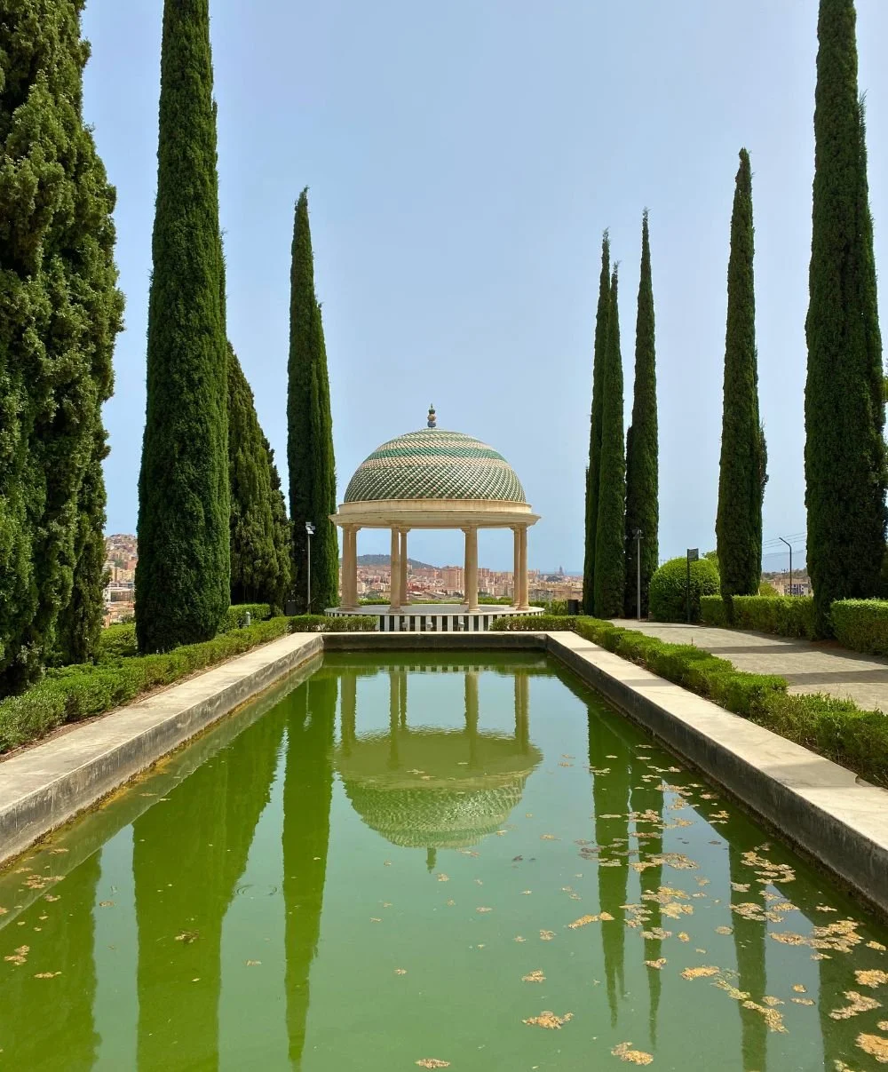 View over the reflecting pool towards the gazebo mirador at Malaga's Jardin Botanico-Historico La Concepcion