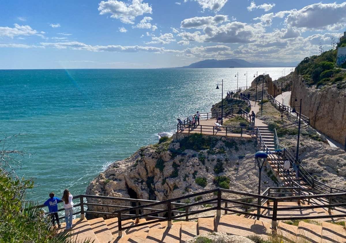 View of the coastal path of the cliffs of El Cantal, on a sunny day with mountains in the distance