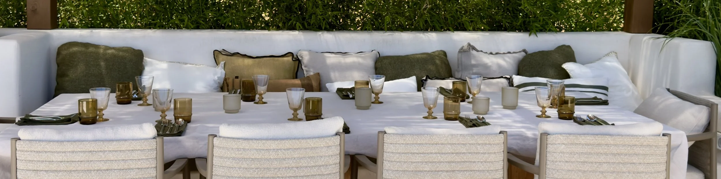 Long outdoor table prepared for a private dining experience surrounded by Mediterranean greenery.