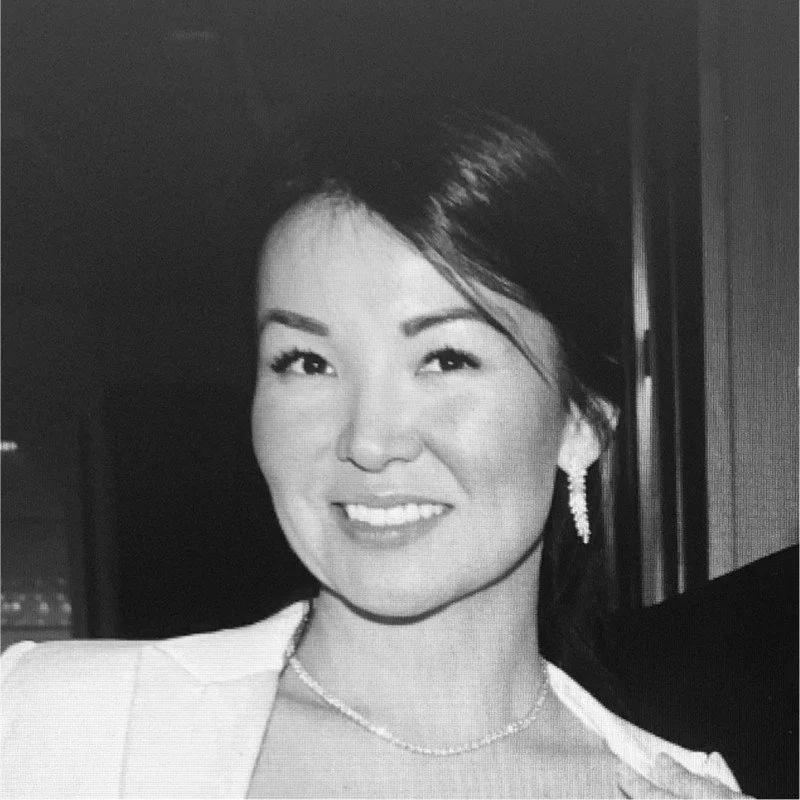 Black and white photo of a woman smiling, wearing earrings and a necklace, in a formal setting.  Professional leader, confident with making change.