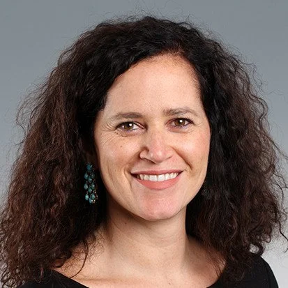 Smiling woman with curly hair and earrings.  Leader of sales team who worked with Executive Coach, Deb Seymour.