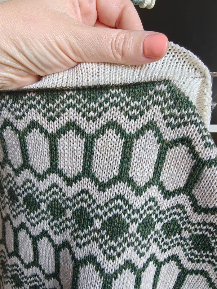 Close up picture of strandhill snood in moss green and light stone colourway being linked by hand.