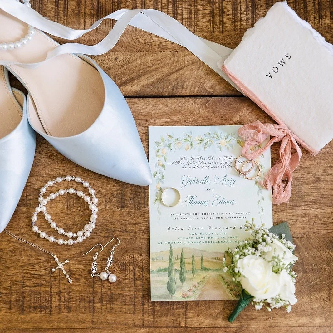 A serene outdoor wedding featuring white florals elegantly accentuated by dark teal. At the ceremony, a carpet of rose petals paved the way to a magnificent overgrown floral arbor. The bridesmaids dressed in color matched dresses while the groomsmen 