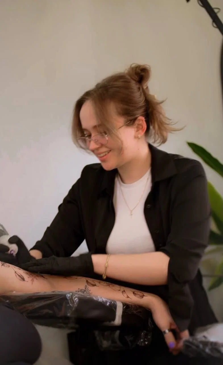 Inna Petrova, Fine Line Tattoo Artist, working on a client's arm tattoo