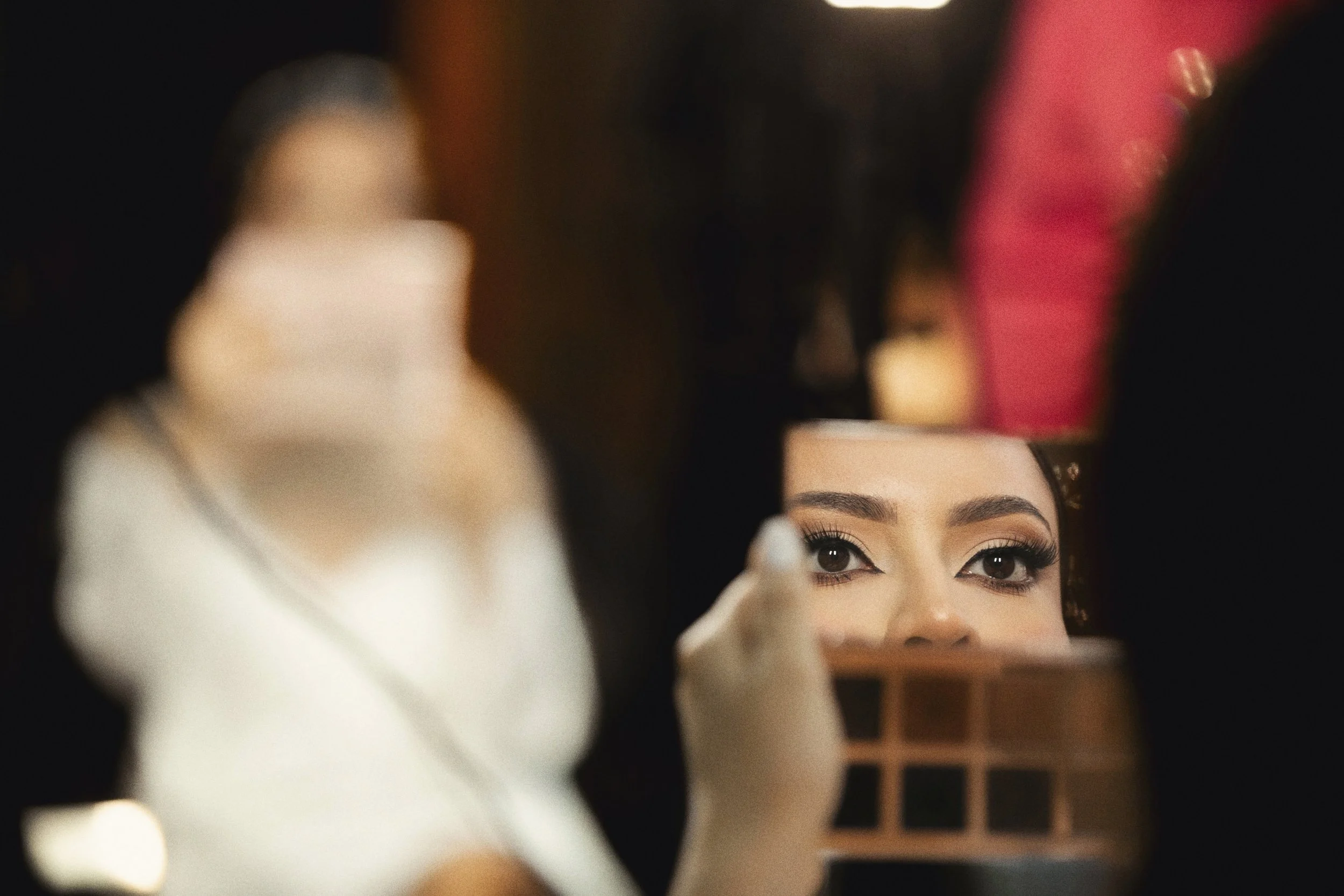 Detalle de rostro de novia reflejado en espejo durante el arreglo final.
