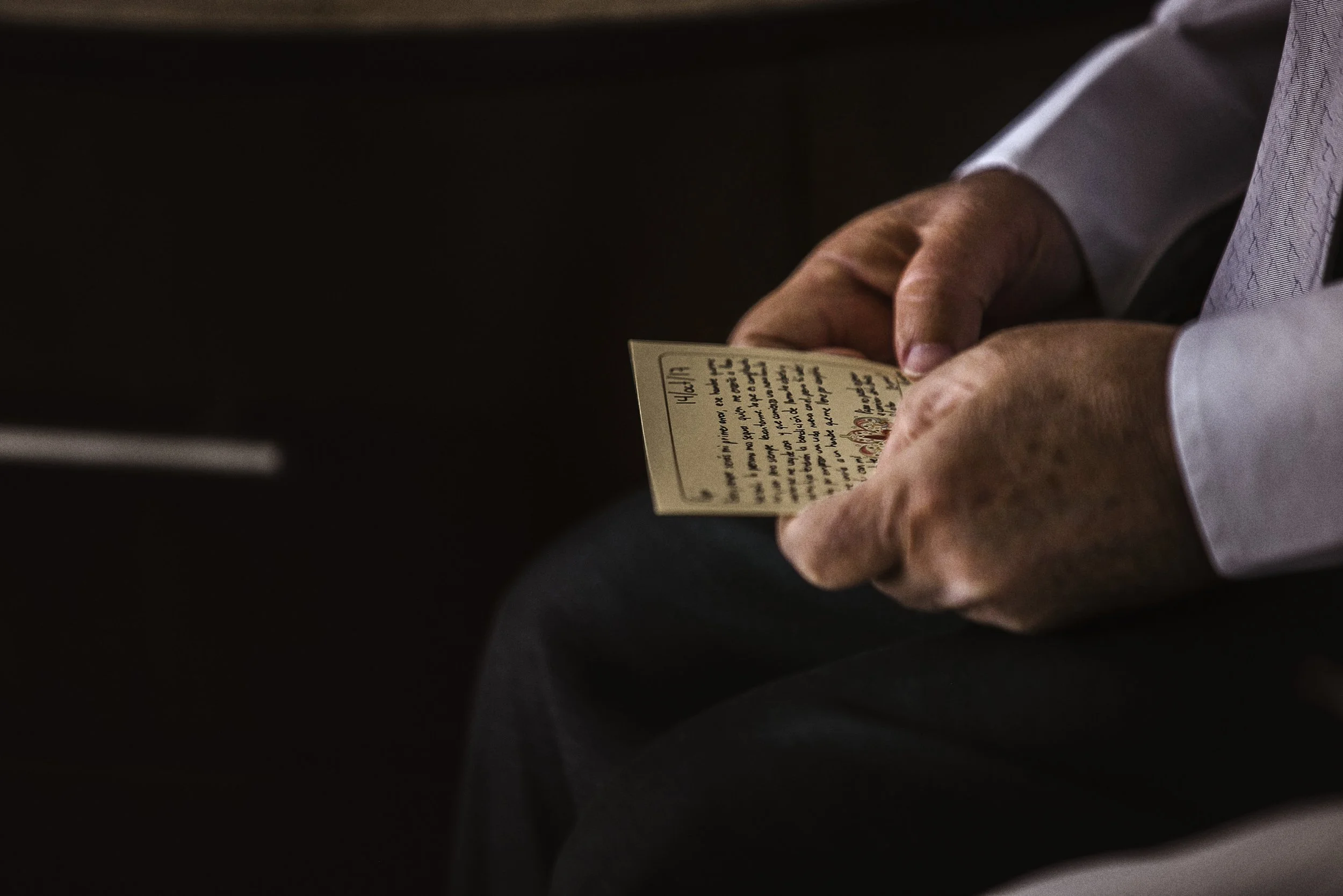 Fotografía documental de mano masculina sosteniendo papel con texto, gesto íntimo previo a la ceremonia.